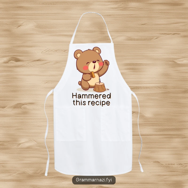 Funny apron showing a determined bear in a workshop setting, enthusiastically hammering a tiny nail into wood with great focus.